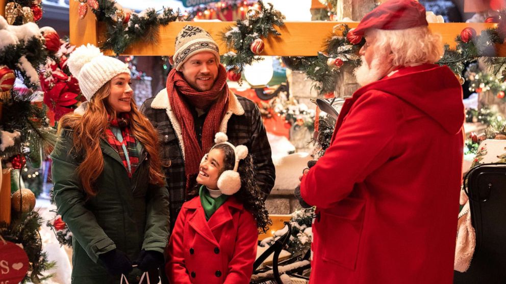 PHOTO: Lindsay Lohan as Sierra, Chord Overstreet as Jake, Olivia Perez as Avy, and Bus Riley as Chestnut Vendor star in "Falling For Christmas" on Netflix. 