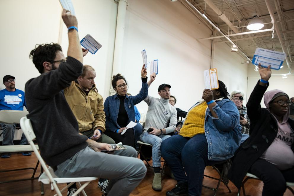 PHOTO: Attendees for Senator Bernie Sanders, an Independent from Vermont and 2020 presidential candidate, hold up their Presidential Preference Cards during the first-in-the-nation Iowa caucus at the Southridge Mall in Des Moines, Iowa, Feb. 3, 2020.