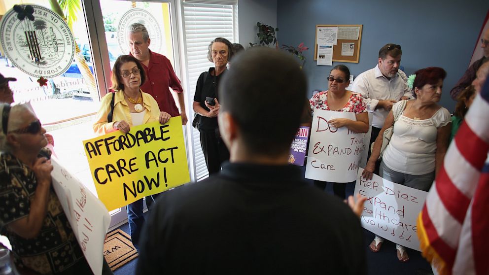 Daniel Martinez (back to camera) an aide to Florida State Rep. Manny Diaz speaks to protesters about Diaz's stance against the expansion of healthcare coverage on September 20, 2013 in Miami. As the protest took place, the Republican led House in Washington, D.C. by a 230-189 tally passed a short-term government spending plan that would eliminate all funding for "Obamacare." 