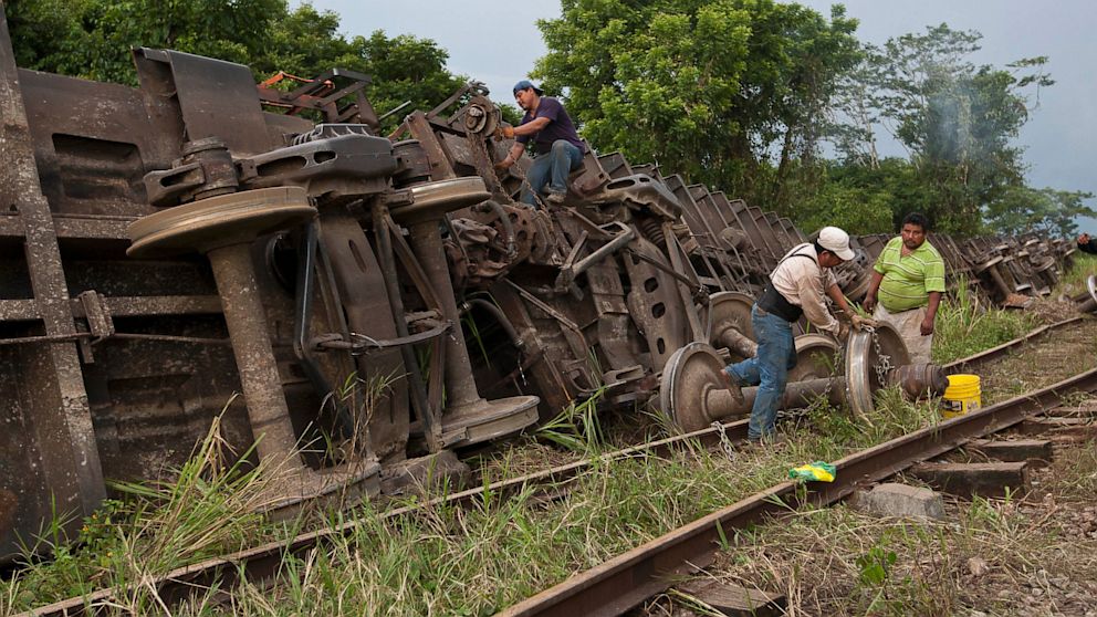 Men work next to a cargo train known as "the Beast," after it derailed near the town of Huimanguillo, southern Mexico, Sunday, Aug.  25, 2013.  The cargo train, carrying at least 250 Central American hitchhiking migrants derailed in a remote region, killing at least five people.
