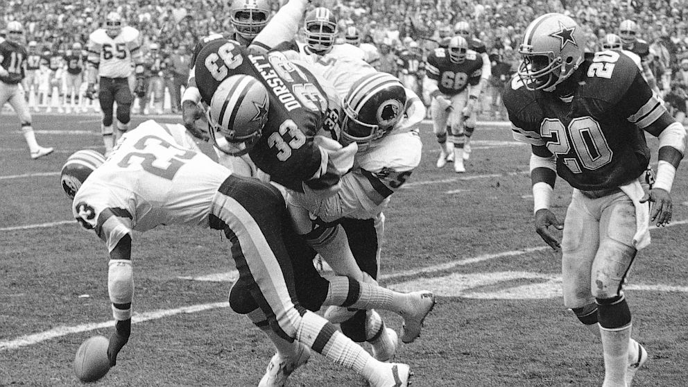 Dallas Cowboys running back and Hall of Famer Tony Dorsett (33) takes a hard hit against the Washington Redskins in Washington. Dorsett was one of 4,500 former players who settled a concussion-related lawsuit with the NFL for $765 million.  (AP Photo/File)