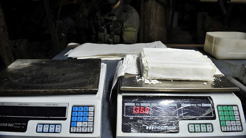 Colombian police personnel from an anti-narcotics unit custody an illegal laboratory producing cocaine hydrochloride.