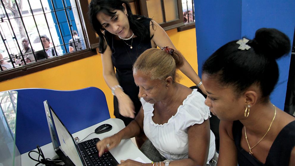 An employee of ETECSA (Cuban telecommunications company) helps a client at a cyber place in Havana on June 4, 2013. 