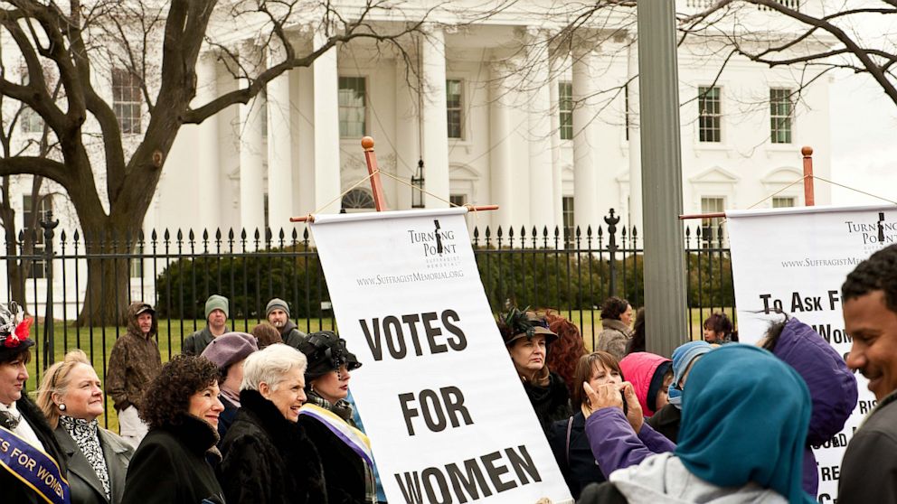 Women hold a sign in front of the White House in Washington on March 2, 2013 during an event to commemorate the 100th anniversary of the Suffrage March. 