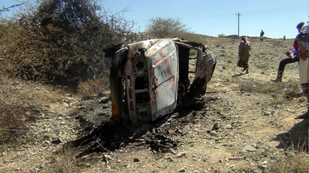 People gather near a destroyed car that was carrying militants in the Sawmaa area of al-Bayda province, Yemen, April 19, 2014.