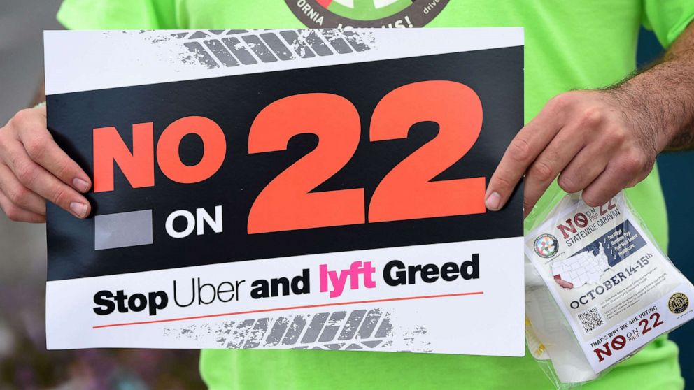 PHOTO: A rideshare driver holds up a sign supporting a no vote on Prop 22 in Oakland, Calif., Oct. 9, 2020. 