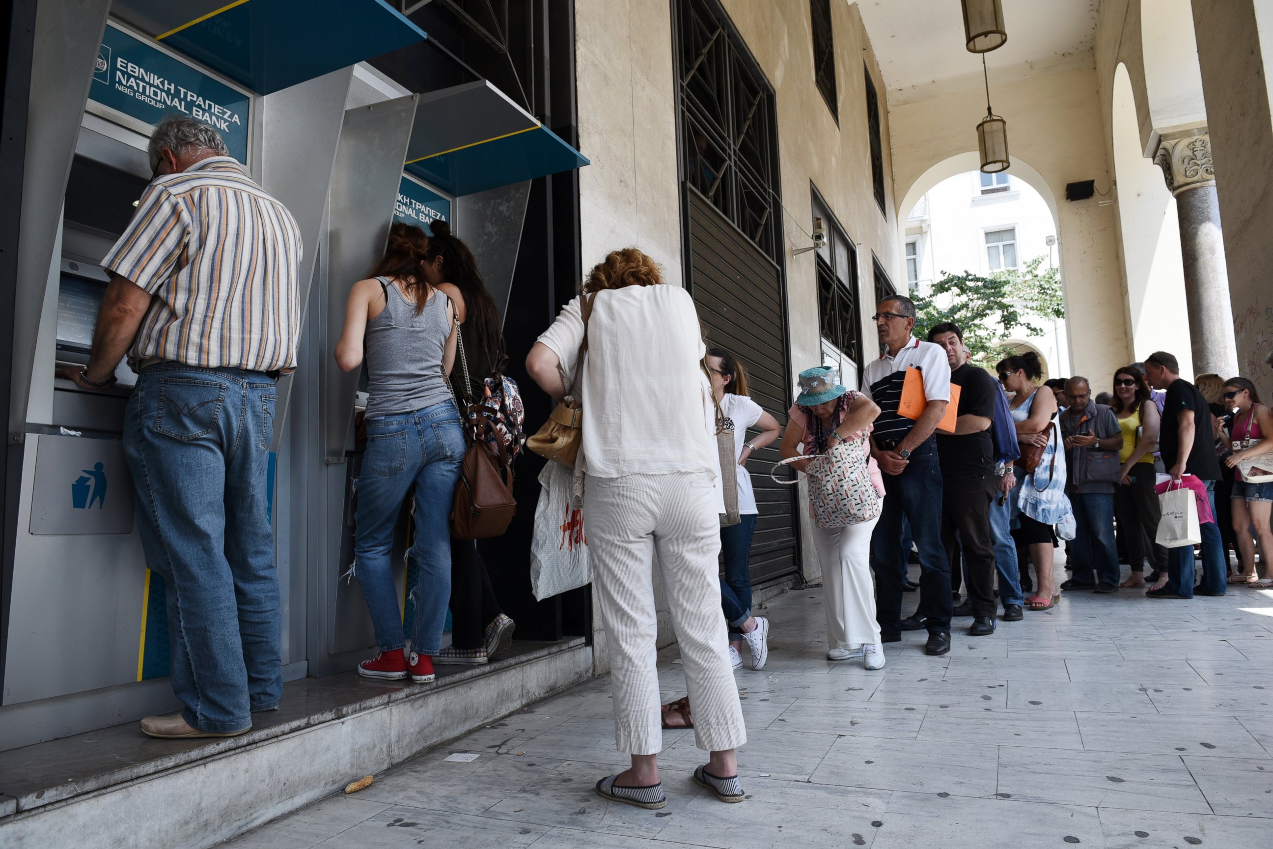 PHOTO: People line up at ATMs outside a National bank branch, June 29, 2015, in the northern Greek port city of Thessaloniki.