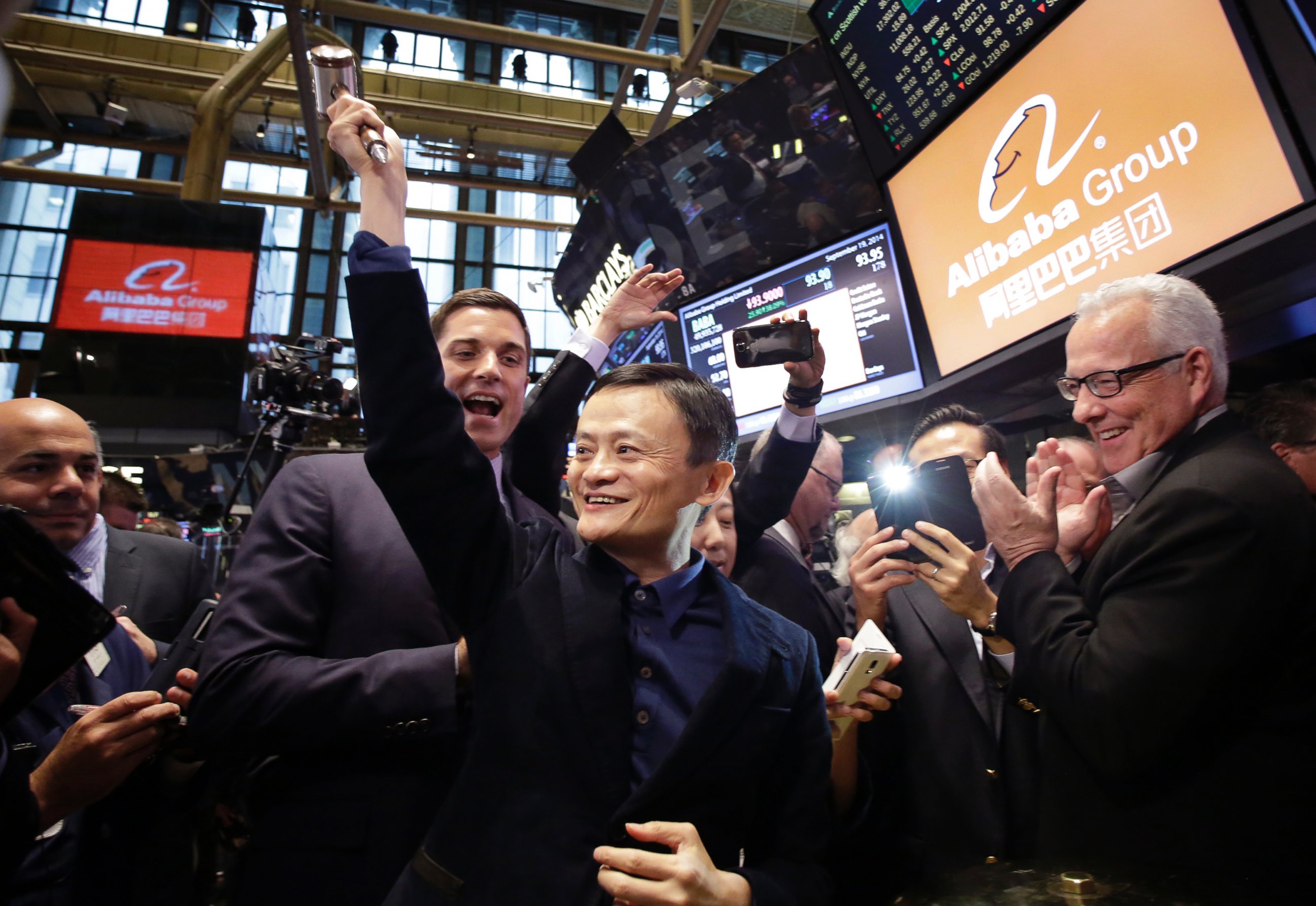 PHOTO: Alibaba founder Jack Ma, center, raises a ceremonial mallet before striking a bell during the company's IPO at the New York Stock Exchange, in New York, Sept. 19, 2014. 