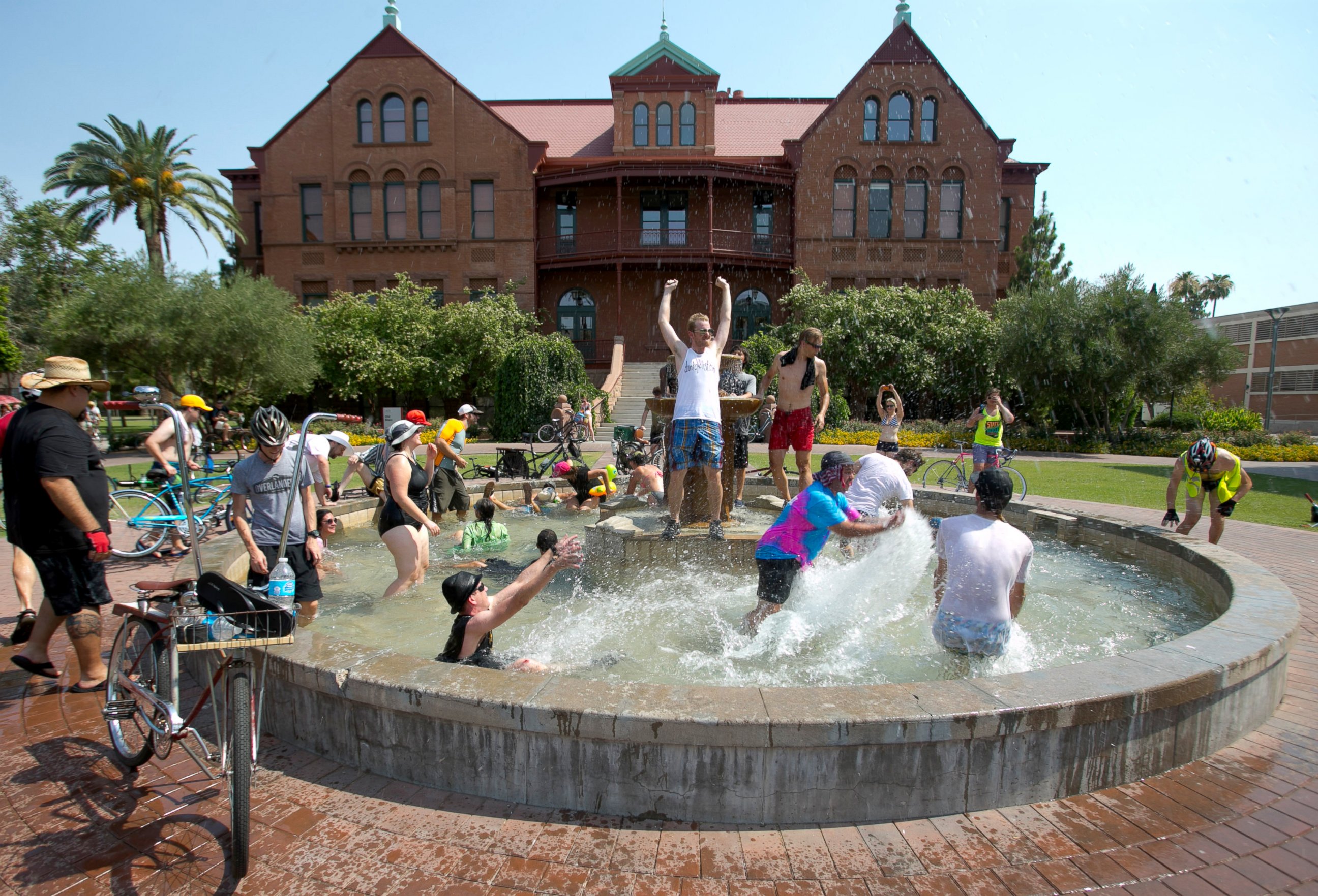PHOTO: People cool off in the fountain in front of Old Main on Arizona State University campus in Tempe, Ariz. during the Tempe Bicycle Action Group swimsuit ride, June 29, 2013. 