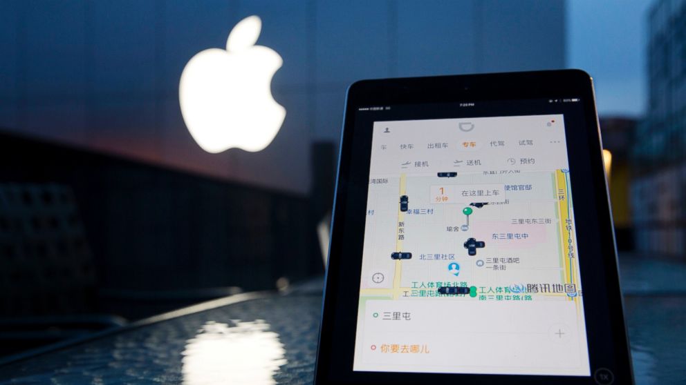 A mobile device displaying the Didi Chuxing app is posed near the Apple store logo in Beijing, China, May 13, 2016. 