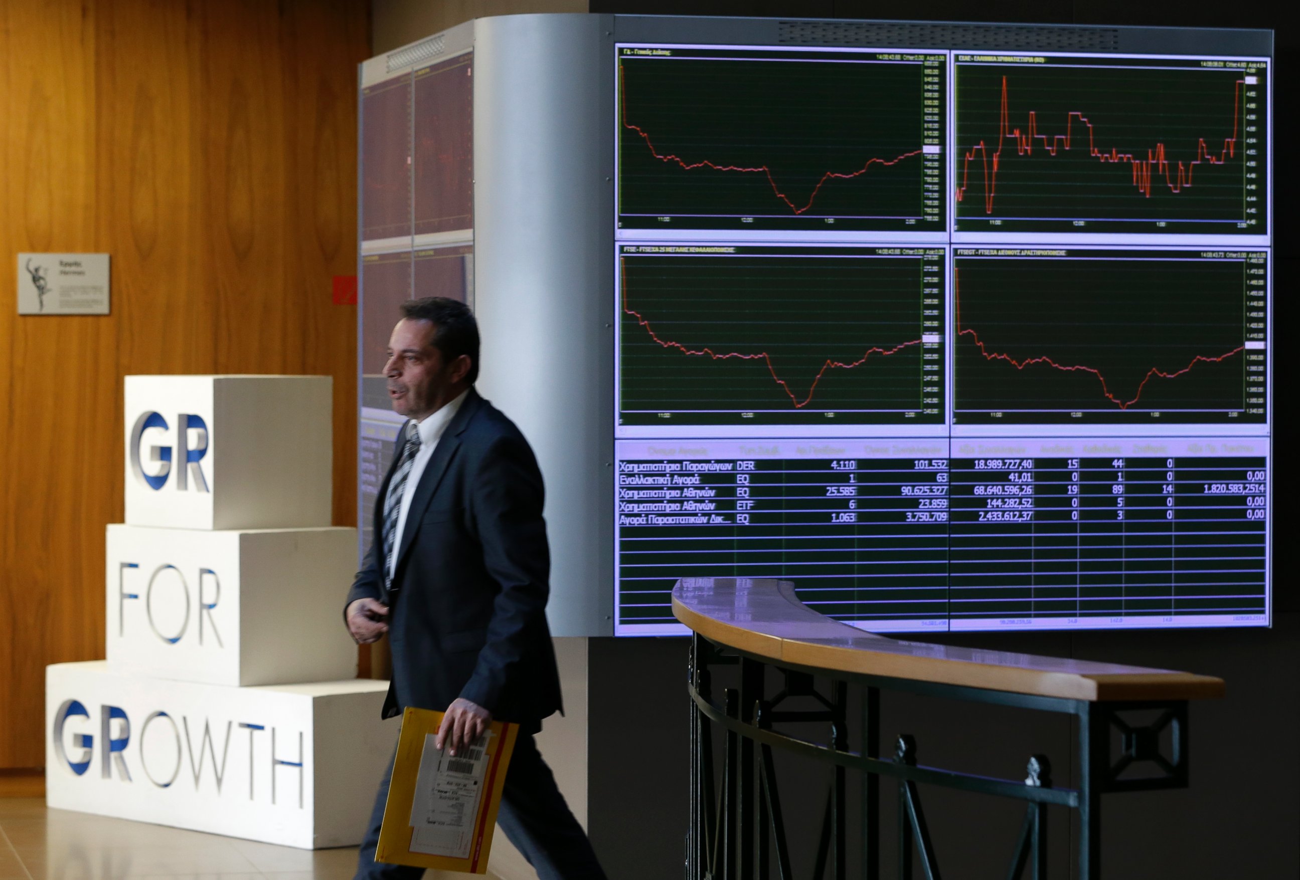 PHOTO: An employee of the Stock Exchange walks next to a display showing stock price movements in Athens, Dec. 29, 2014.
