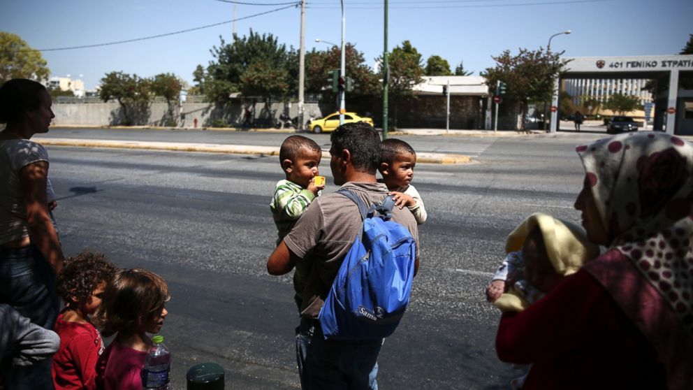 Refugees prepare to cross a street as they leave a building of the Greek Asylum service in Athens, Aug. 19, 2016. 