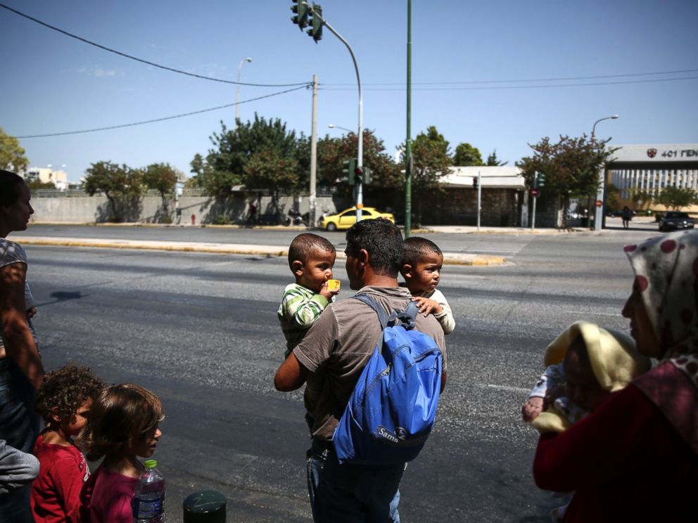 PHOTO: Refugees prepare to cross a street as they leave a building of the Greek Asylum service in Athens, Aug. 19, 2016.
