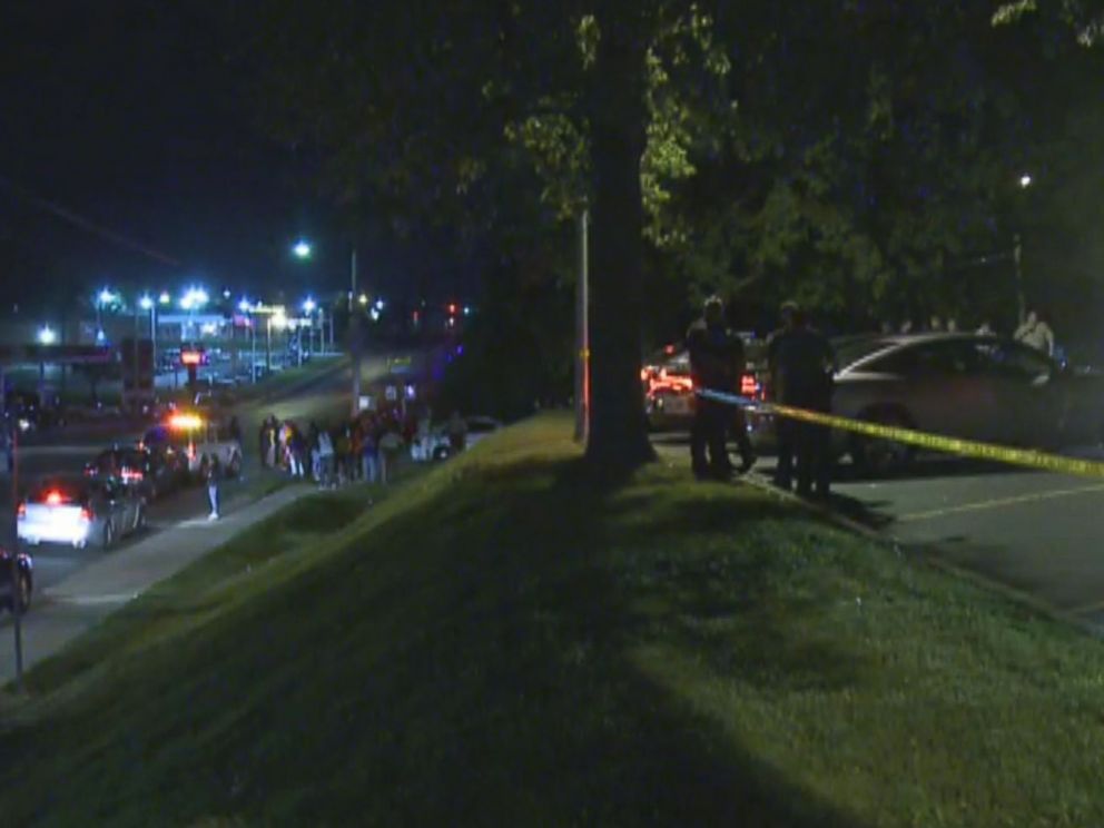 PHOTO: Police watch, right, as a crowd gathers near the scene where a police officer was shot in the arm Saturday night Sept. 27, 2014 in Ferguson, Mo.