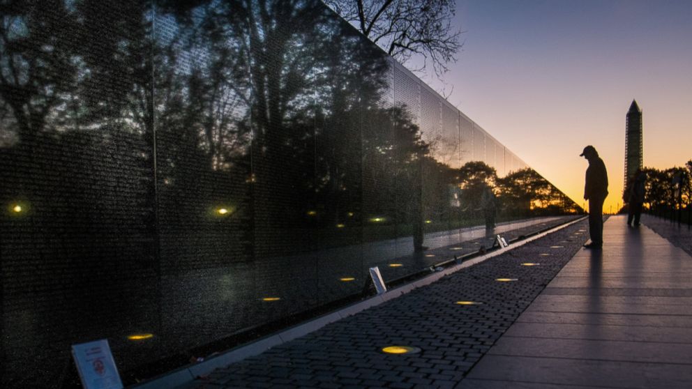 A visitor at the Vietnam Veterans Memorial in Washington passes early in the morning on Veterans Day, Nov. 11, 2013, to look at the names inscribed on the wall. 