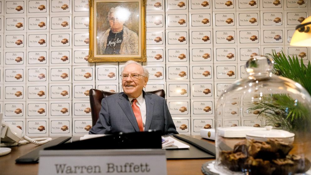 Warren Buffett sits behind a desk under a portrait of founder Mary See at the See's Candies booth during a part of the Berkshire Hathaway Annual Shareholders Meeting, April 29, 2016, in Omaha.