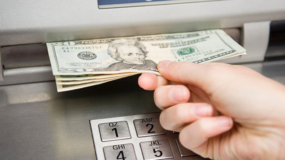 In this stock image, a person is seen withdrawing cash from an ATM machine. 
