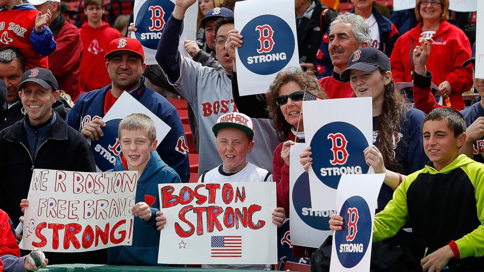 Fans hold a sign to honor the Marathon bombing victims, before a game against the Kansas City Royals at Fenway Park, April 20, 2013, in Boston.