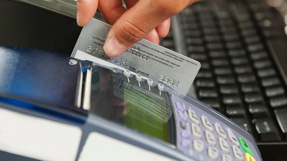 In this stock image, a woman is pictured swiping her debit card for a purchase. 