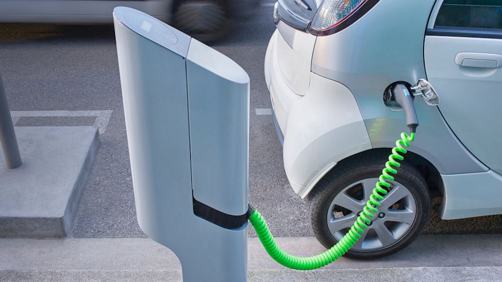 An electric car charges at a charging station.
