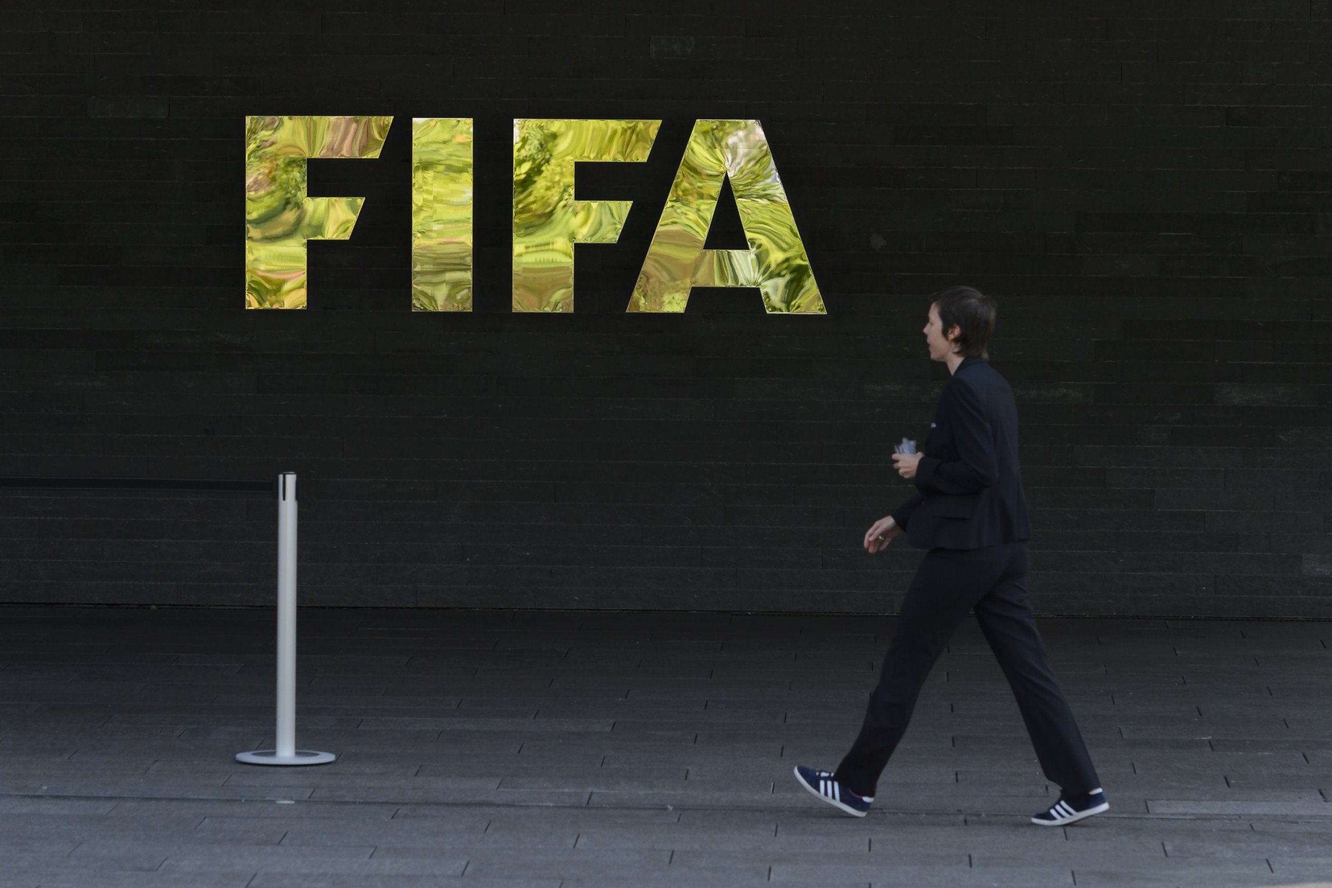 PHOTO: A woman walks by a logo of international football's top body FIFA, at the organization's headquarters, on May 27, 2015 in Zurich. 