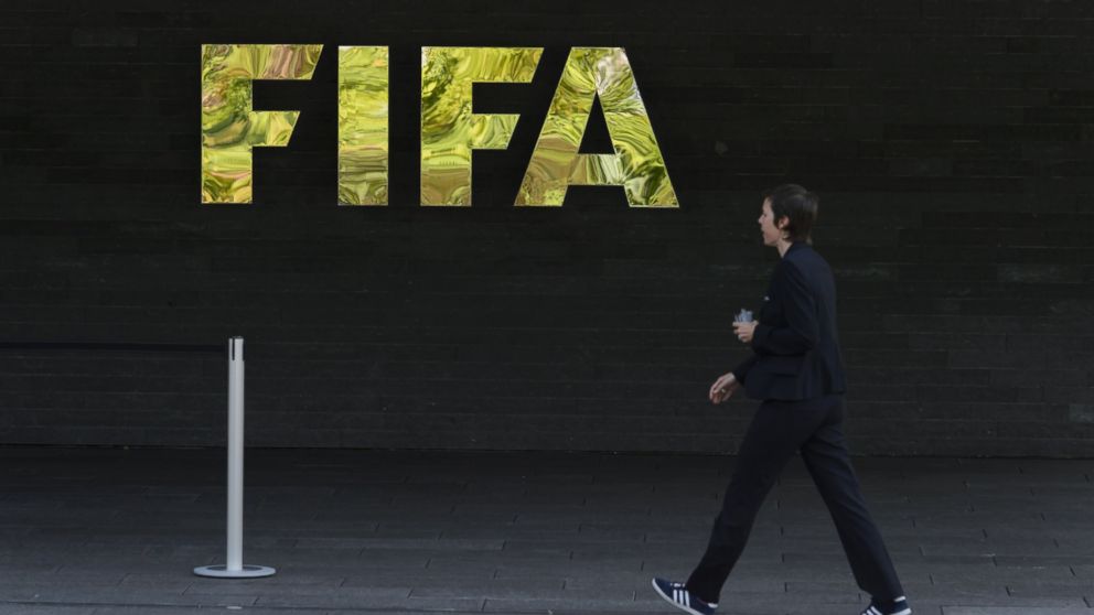 PHOTO: A woman walks by a logo of international football's top body FIFA, at the organization's headquarters, on May 27, 2015 in Zurich. 