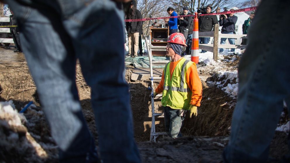 Camera crews look on as workers replace an old lead pipe with a new safer copper pipe at a home in Flint, Michigan, March 4, 2016.

The city exposed 100,000 residents to lead poisoning after cutting water treatment costs.  / AFP / Geoff Robins        (Photo credit should read GEOFF ROBINS/AFP/Getty Images)