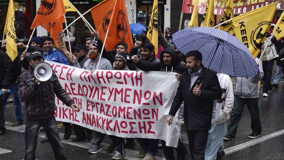Unpaid migrant workers from recycling companies join a protest march led by laid-off civil sector employees in central Athens, Dec. 17, 2014.
