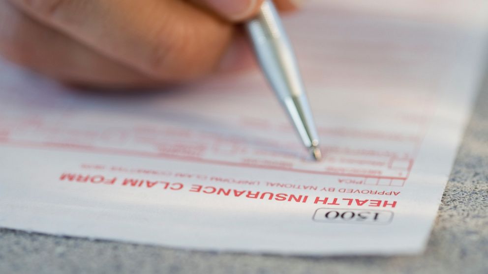 A man filling out a health insurance claim form is pictured in this stock image.