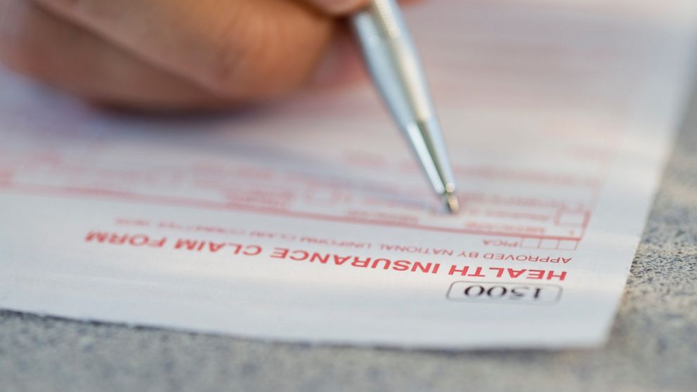 A man is pictured filling out a health insurance claim form.