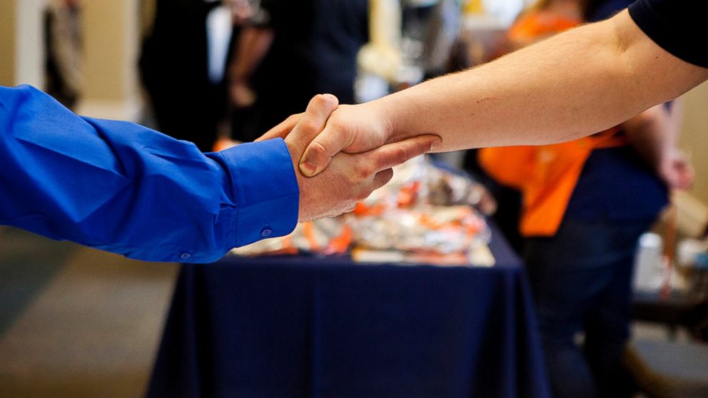 A job seeker shakes hands with a representative at the Recruit Military veteran job fair in San Diego, Feb. 27, 2014. More Americans than forecast filed applications for unemployment benefits last week, a sign the labor market is improving in fits and starts.