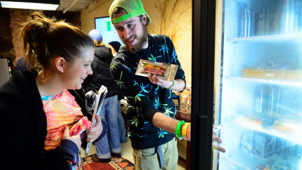 PHOTO: Garrett Sellars shows an edible to Ashly Carius, both of Oklahoma City, at LoDo Wellness. The first day of retail sales of marijuana in Colorado was Jan. 1, 2014.
