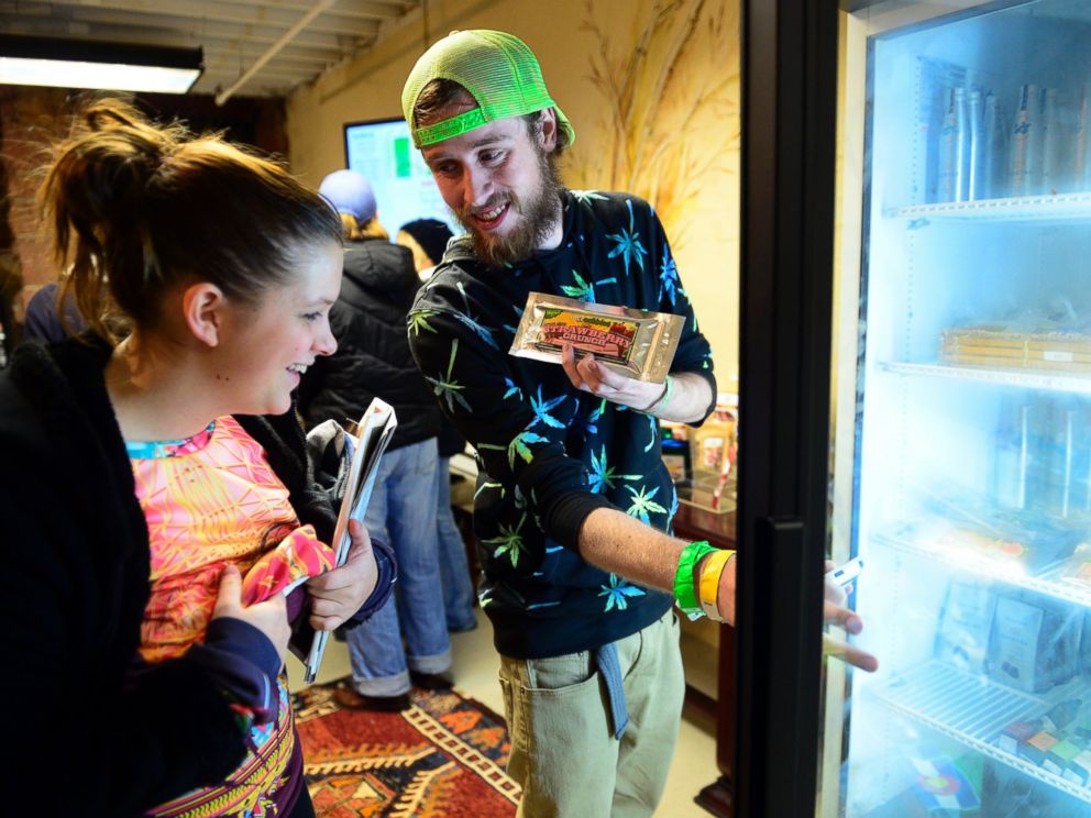 PHOTO: Garrett Sellars shows an edible to Ashly Carius, both of Oklahoma City, at LoDo Wellness. The first day of retail sales of marijuana in Colorado was Jan. 1, 2014.