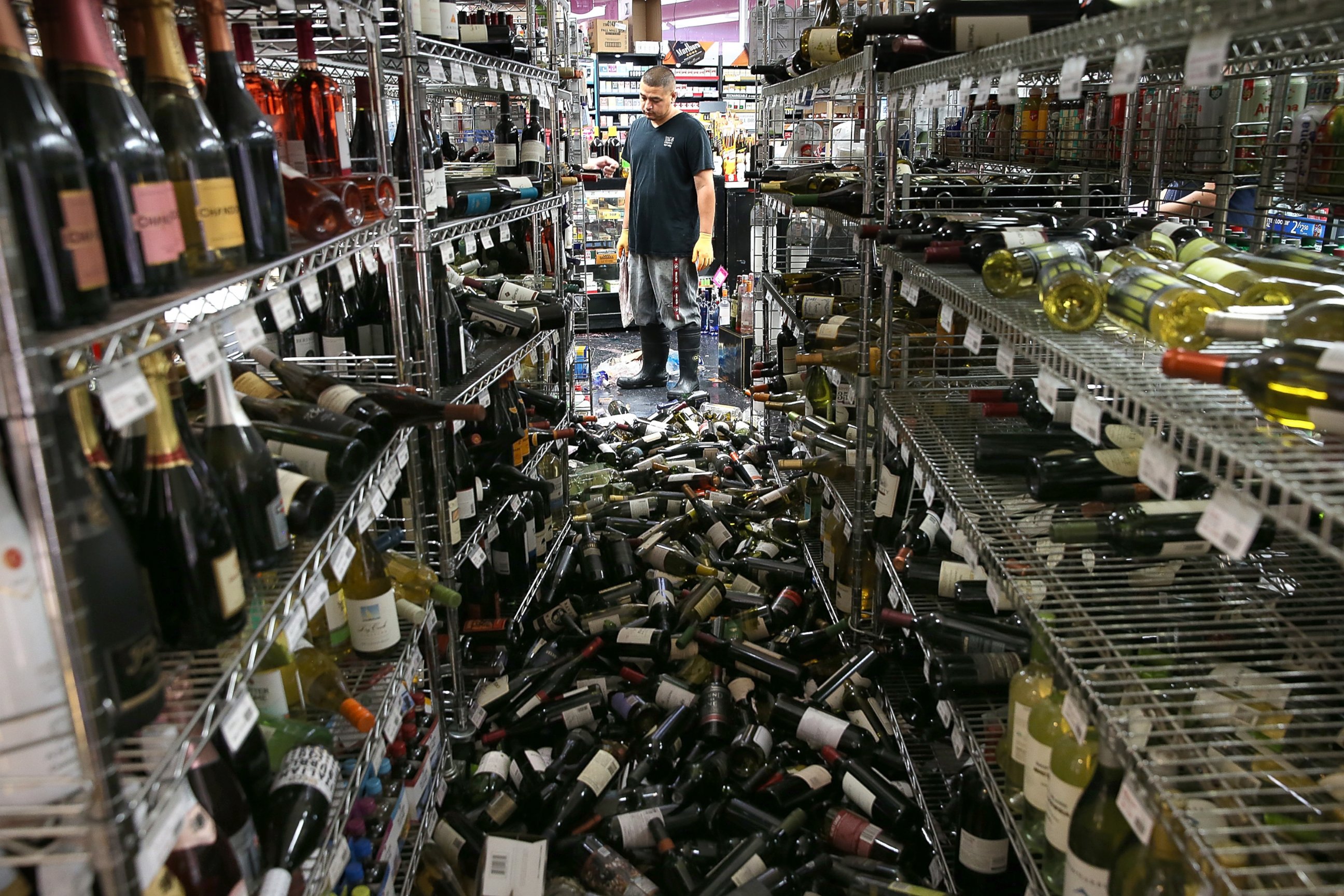 PHOTO: A worker looks at a pile of wine bottles that were thrown from the shelves at Van's Liquors following a reported 6.0 earthquake on Aug. 24, 2014 in Napa, Calif. 