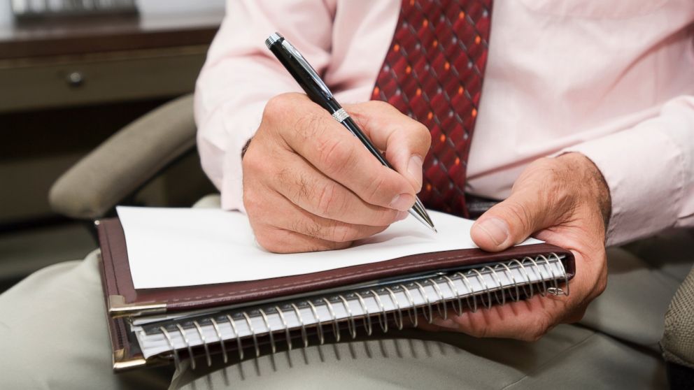 A psychologist jots down some notes with a pen while in session with a client.