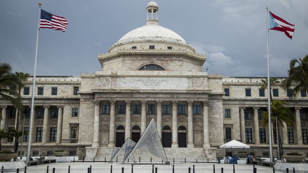 A Puerto Rican and an American flag fly outside the Capitol of Puerto Rico, May 1, 2016, in San Juan, Puerto Rico.
