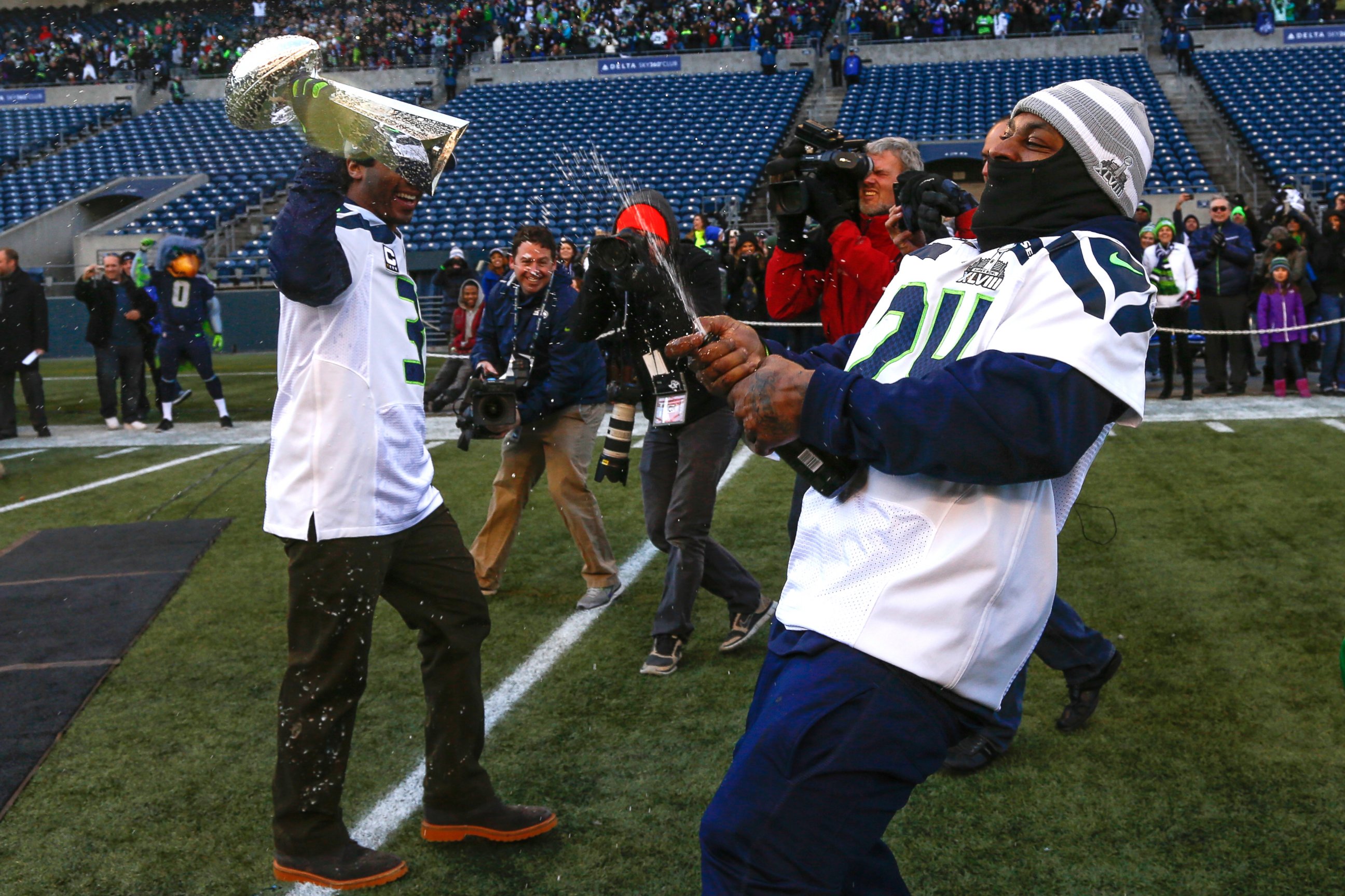 PHOTO: Quarterback Russell Wilson of the Seattle Seahawks holds the Lombardi Trophy as Running back Marshawn Lynch uncorks a bottle of champagne at CenturyLink Field, Feb. 5, 2014, in Seattle.