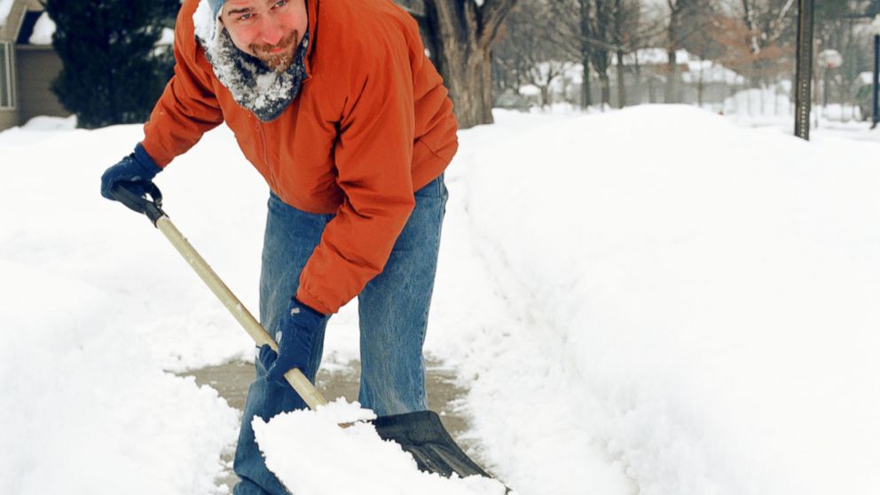 A man shovels snow using a shovel with a D-grip handle. 
