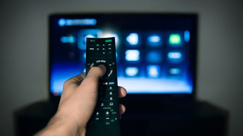 A man is pictured using a remote control for his television in this stock image. 
