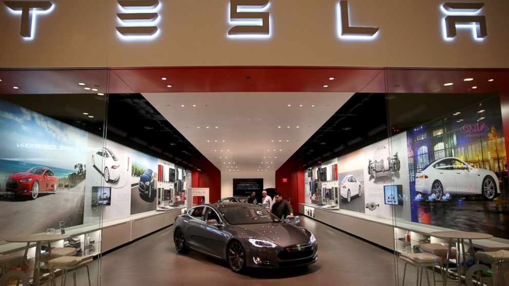 People look at a Tesla Motors vehicle on the showroom floor at the Dadeland Mall in Miami, Fla., Feb. 19, 2014.