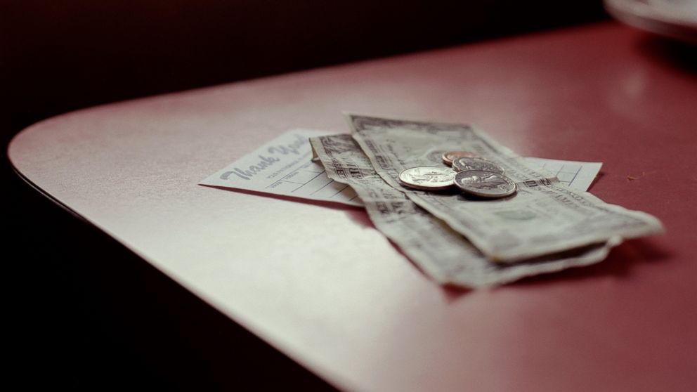 A tip sits on top of a check at a restaurant.
