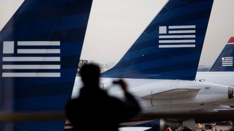 In this file photo, the silhouette of a traveler is seen taking a photograph of US Airways planes parked on the tarmac at Ronald Reagan National Airport in Washington, D.C. on Nov. 15, 2013.