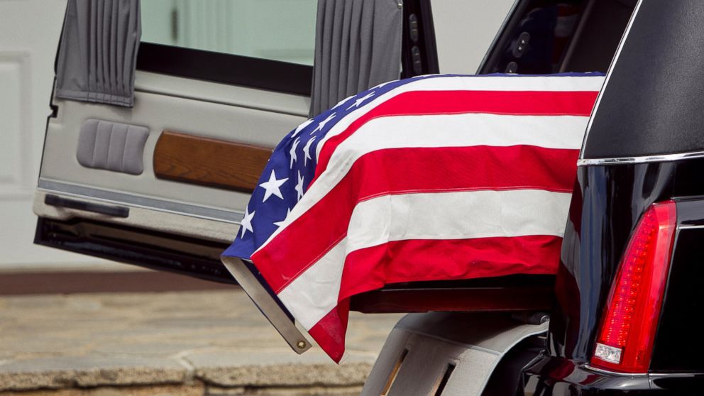 PHOTO: An American flag over a casket at a funeral.