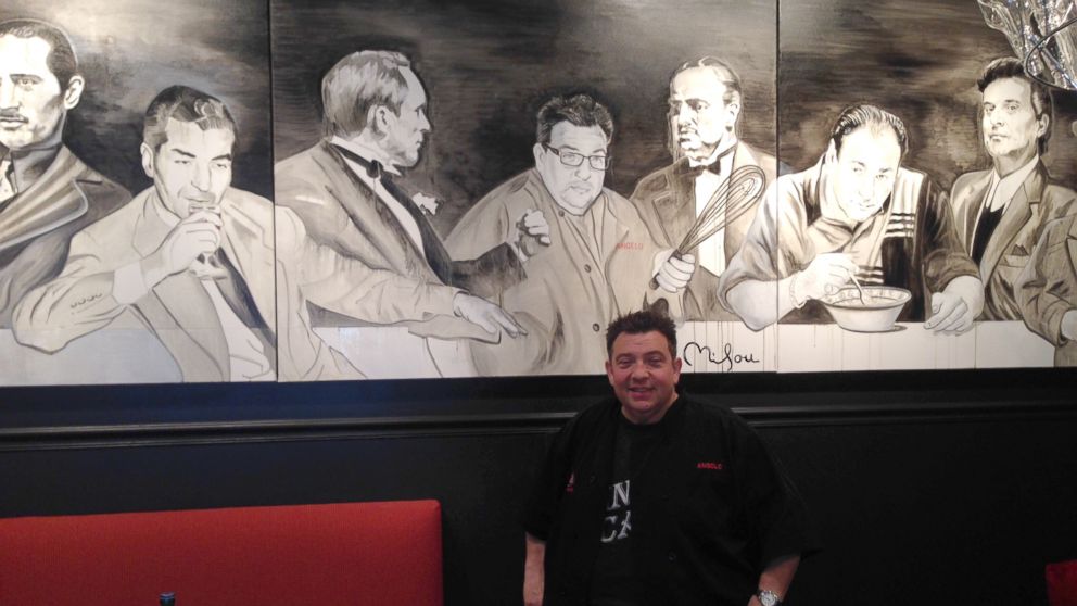 PHOTO: Angelo Lutz, is pictured in front of a mural at his restaurant The Kitchen Consigliere, with depictions of the world-famous real and fictitious gangsters.