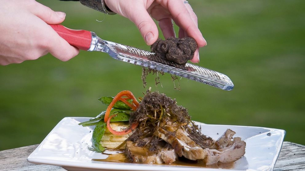 Truffles are shaved over a plate of food.