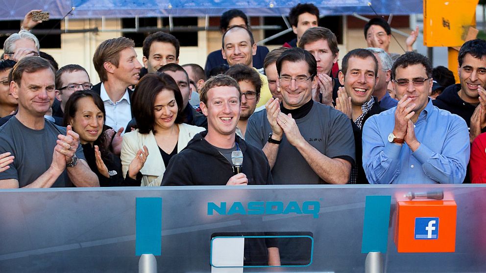 Mark Zuckerberg, CEO and founder of Facebook, and COO Sheryl Sandberg gather with a throng of cheering employees at the company headquarters in Menlo Park, Calif. to ring the stock market's opening bell, May 18, 2012. 