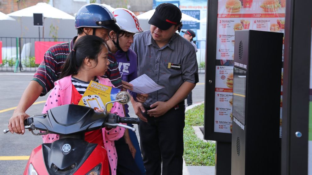 Customers on scooters learn how to order at the drive-thru at the first McDonald's drive-thru restaurant in Ho Chi Minh City, Vietnam, Feb. 10, 2014. 