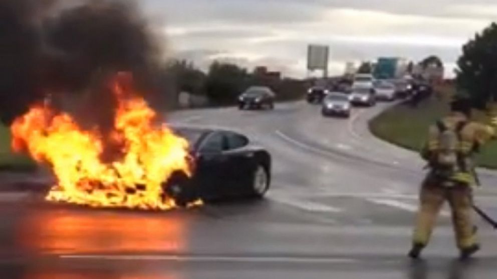 In this image from a YouTube video, a firefighter arrives to extinguish a burning Tesla Model S on Washington State Route 167 outside of Seattle.