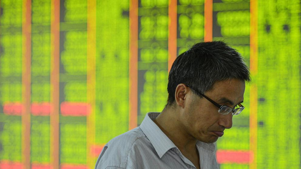 PHOTO: A man walks past a screen showing stock market movements at a securities company in Hangzhou, in eastern China's Zhejiang province, on April 7, 2025.