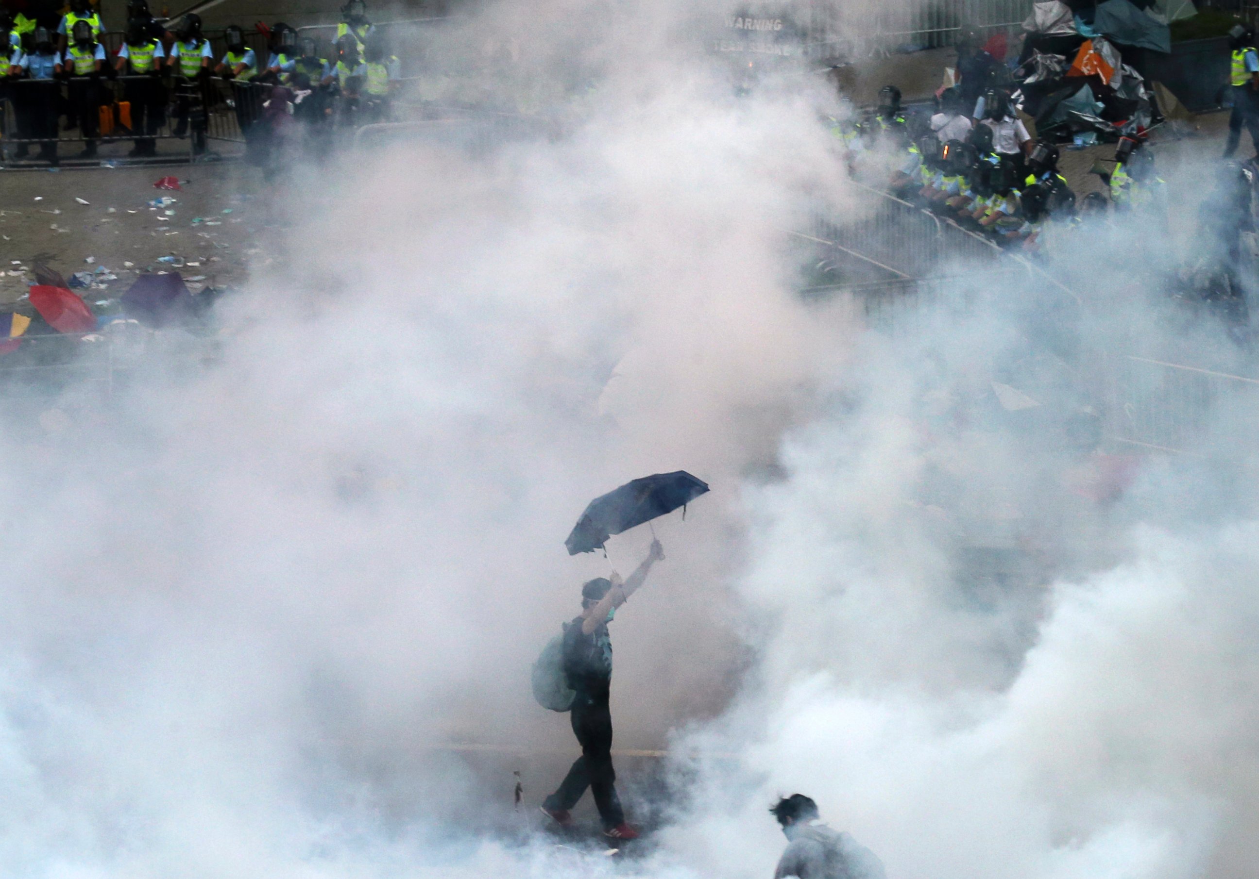 PHOTO: A protester walks in tear gas fired by riot policemen after thousands of protesters blocking the main street to the financial Central district outside the government headquarters in Hong Kong, Sept. 28, 2014.